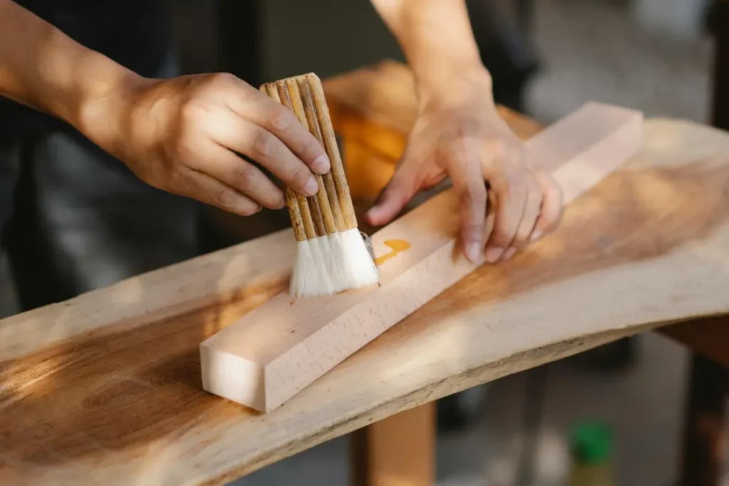 Worker applying wood polish and finishing treatment on wooden surface using professional method